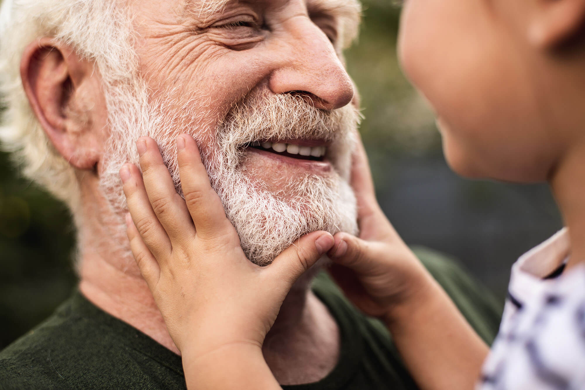Old smiling man and his granddaughter looking each other